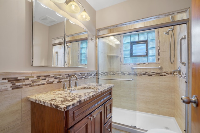 bathroom featuring tile walls, walk in shower, tasteful backsplash, and large vanity