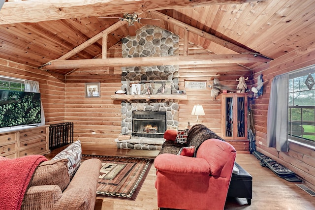 living room with lofted ceiling with beams, wood ceiling, a stone fireplace, and light wood-type flooring