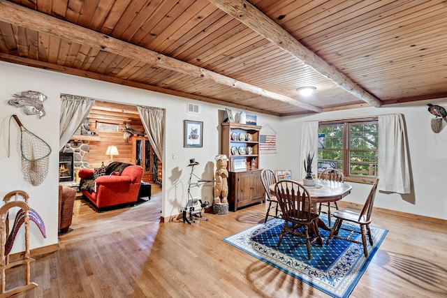 dining room featuring beam ceiling, light hardwood / wood-style floors, a fireplace, and wood ceiling