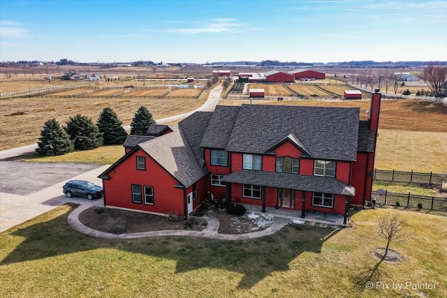 view of front of home with a rural view and a front lawn