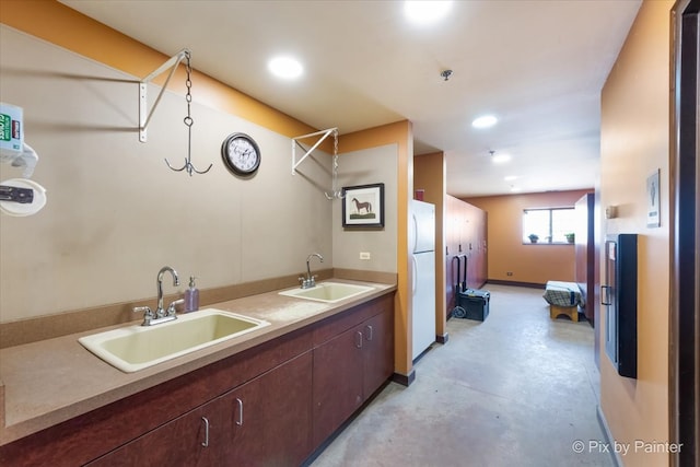 kitchen featuring dark brown cabinets, sink, and white fridge