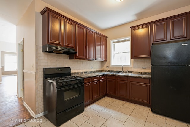 kitchen with dark stone counters, tasteful backsplash, black appliances, sink, and light tile flooring