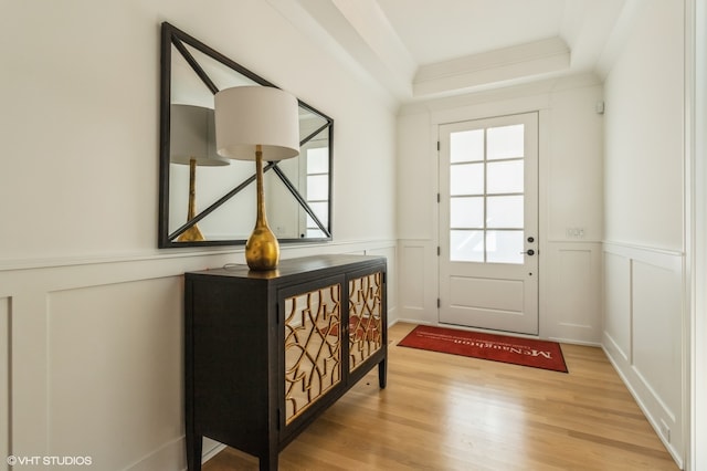 doorway with light hardwood / wood-style flooring and a tray ceiling