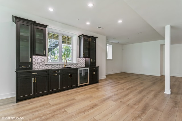 bar featuring wine cooler, sink, light hardwood / wood-style flooring, and decorative backsplash