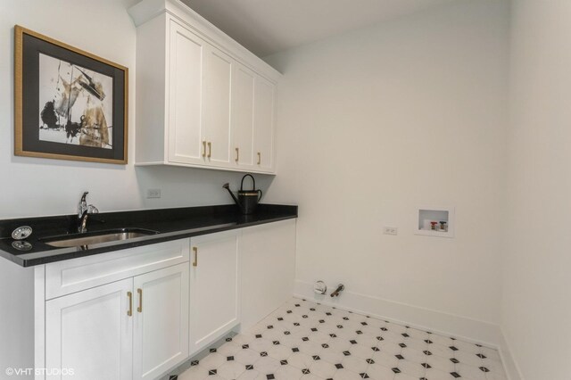 laundry area featuring washer hookup, light floors, cabinet space, a sink, and baseboards