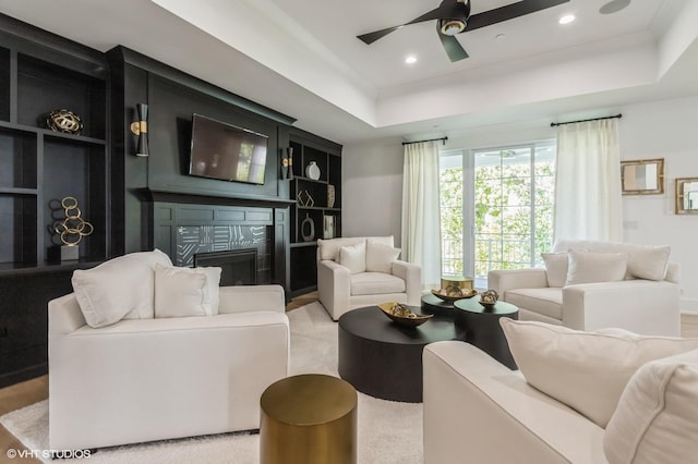 living room with ceiling fan, recessed lighting, a fireplace, built in features, and a raised ceiling