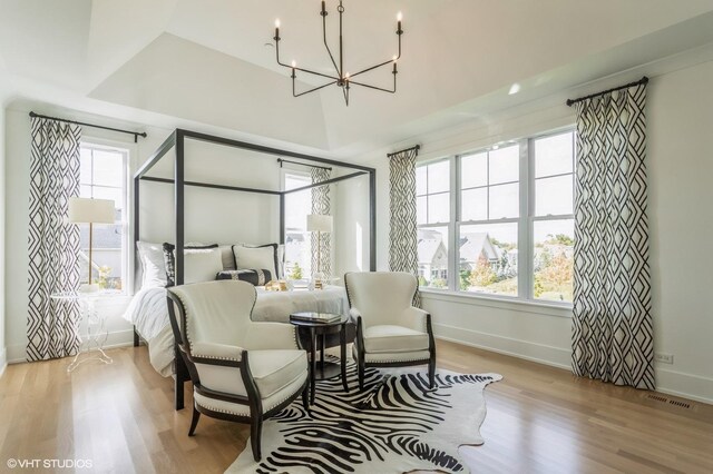 bedroom featuring a tray ceiling, light hardwood / wood-style floors, and a chandelier