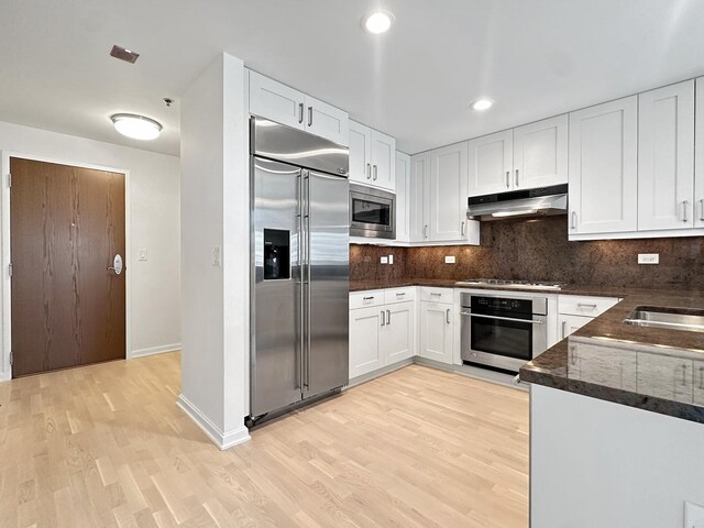 kitchen with light wood-type flooring, built in appliances, and white cabinetry