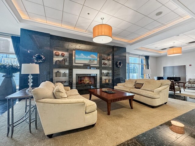 living room featuring a tray ceiling and a fireplace