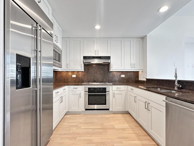 kitchen featuring light hardwood / wood-style floors, built in appliances, sink, and white cabinetry