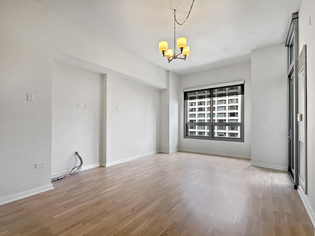 unfurnished room with hardwood / wood-style flooring and an inviting chandelier