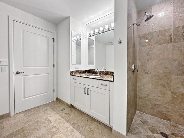 bathroom with a tile shower, vanity, and tile patterned floors