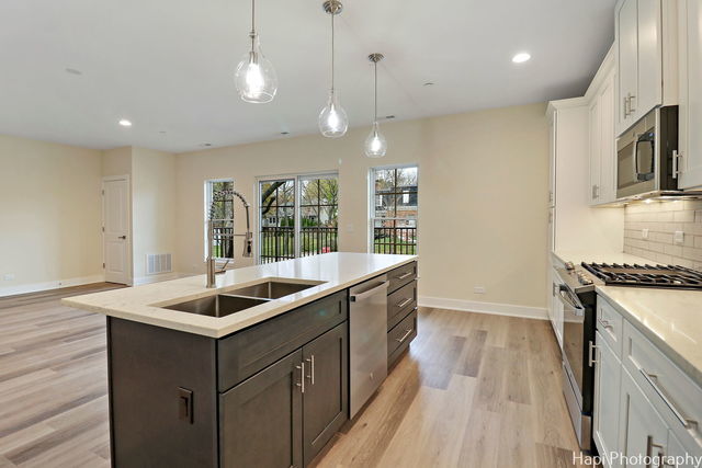 kitchen featuring sink, an island with sink, dark brown cabinets, white cabinets, and appliances with stainless steel finishes