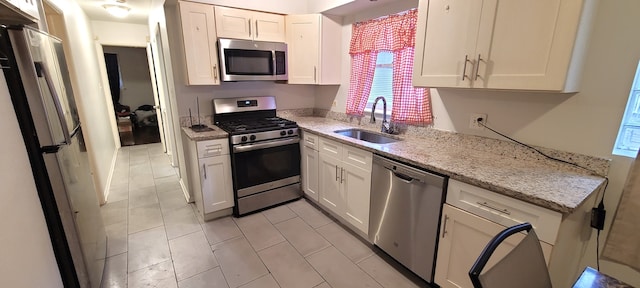 kitchen with light tile floors, white cabinetry, sink, and stainless steel appliances