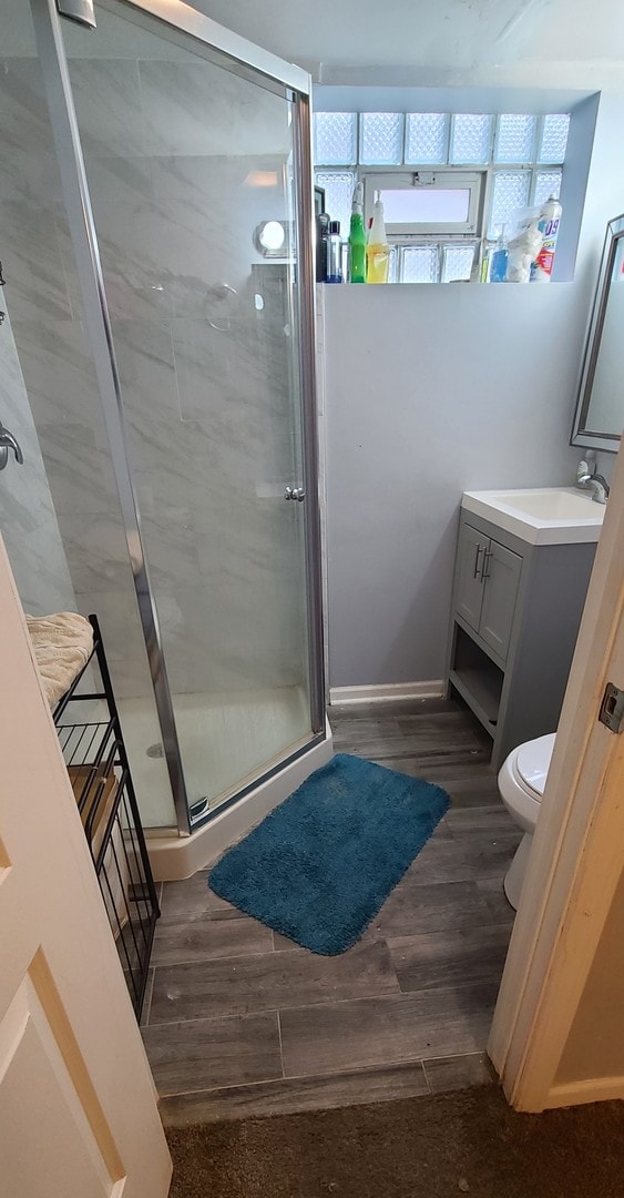 bathroom featuring vanity, toilet, a shower with shower door, and hardwood / wood-style flooring