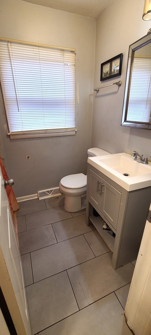 bathroom with toilet, tile flooring, and vanity