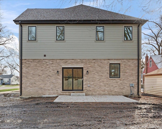 back of property featuring brick siding, roof with shingles, and a patio area