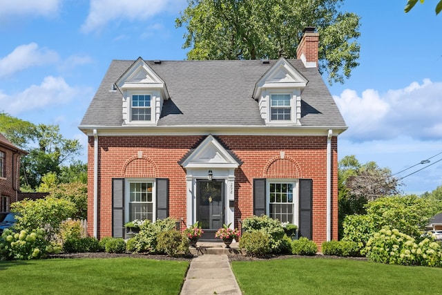 298 Dickens St, Northfield, IL 60093 - colonial-style house featuring brick siding, a front lawn, a chimney, and roof with shingles