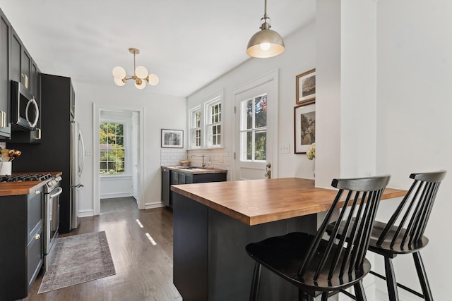 298 Dickens St, Northfield, IL 60093 - kitchen featuring butcher block counters, appliances with stainless steel finishes, a sink, dark wood-style floors, and a kitchen bar