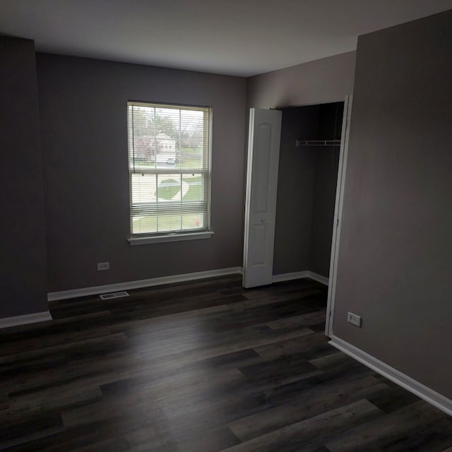 unfurnished bedroom with dark hardwood / wood-style floors and a closet