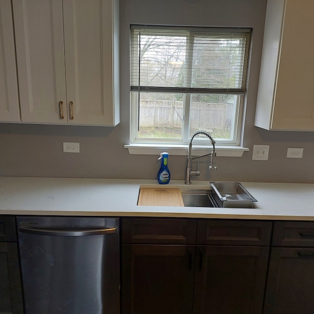 kitchen with stainless steel dishwasher, sink, and white cabinets