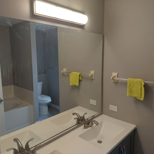 bathroom featuring a bath to relax in, double sink vanity, and toilet