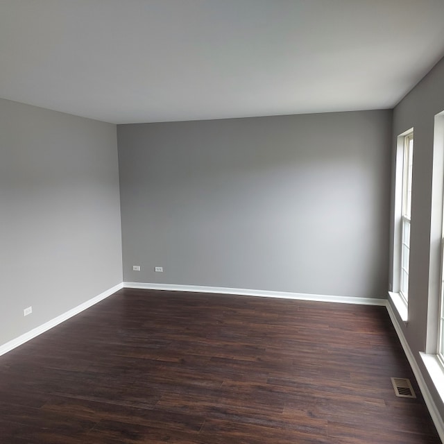 unfurnished room featuring plenty of natural light and dark hardwood / wood-style flooring