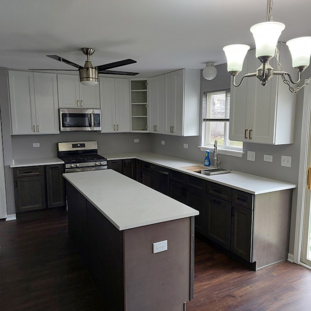 kitchen featuring ceiling fan with notable chandelier, appliances with stainless steel finishes, sink, dark hardwood / wood-style flooring, and pendant lighting