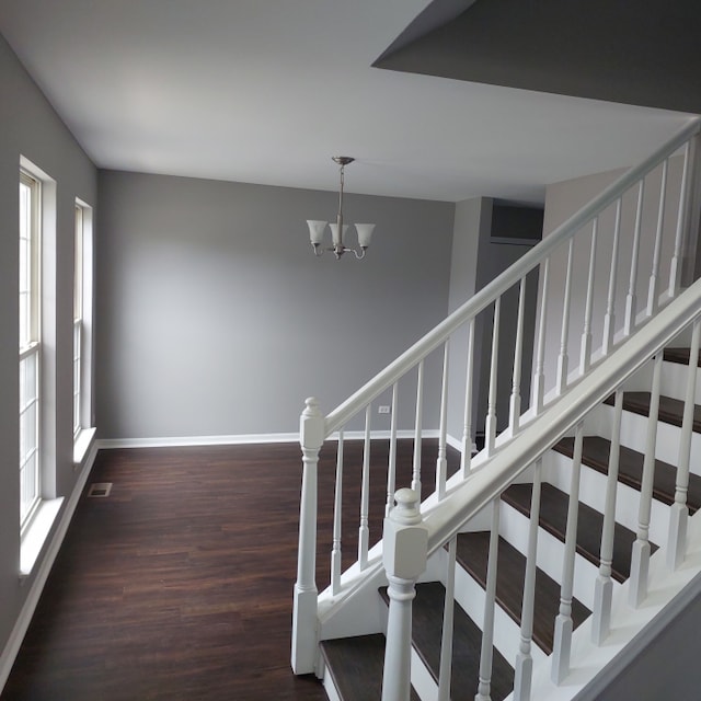 staircase with dark hardwood / wood-style flooring and a chandelier