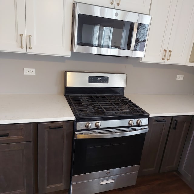 kitchen with stainless steel appliances, white cabinetry, dark hardwood / wood-style flooring, and dark brown cabinetry