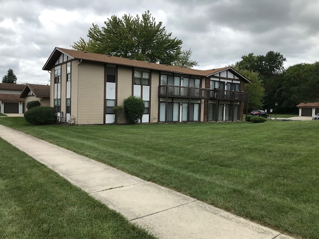 rear view of property with a balcony and a yard