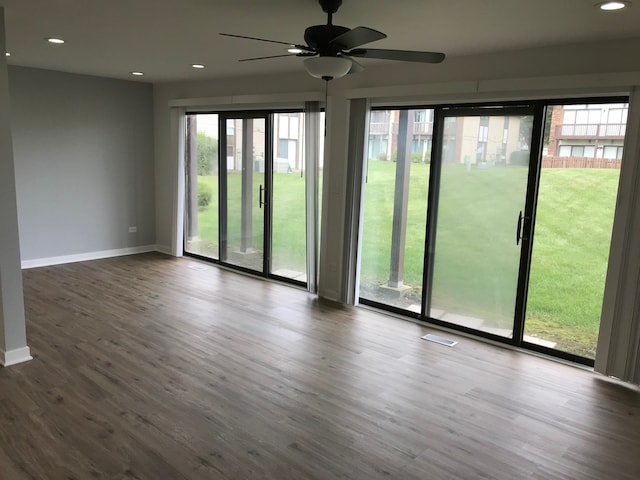 spare room featuring ceiling fan, dark wood-type flooring, and a healthy amount of sunlight