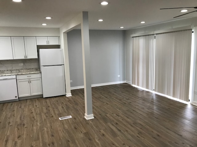 kitchen with tasteful backsplash, white appliances, white cabinetry, and dark hardwood / wood-style flooring