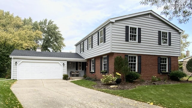 colonial-style house featuring a front yard, driveway, an attached garage, a chimney, and brick siding