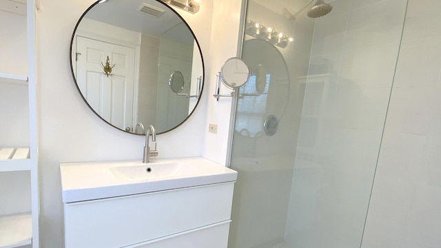 bathroom with visible vents, a walk in shower, and vanity