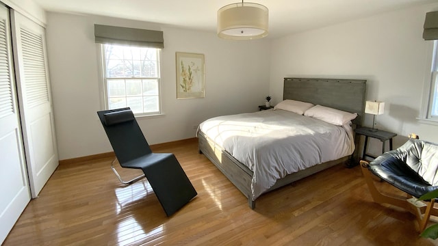 bedroom featuring a closet, light wood-type flooring, and baseboards