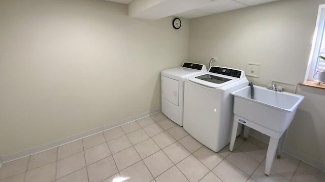 washroom with baseboards, light tile patterned flooring, laundry area, and washer and clothes dryer