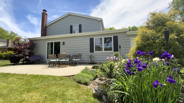 back of house featuring a yard, a chimney, and a patio area