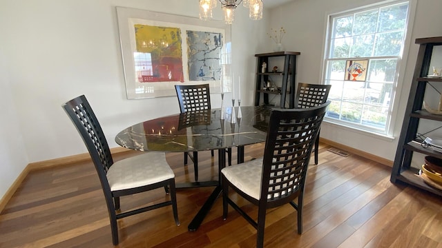 dining space featuring a chandelier, baseboards, visible vents, and wood finished floors