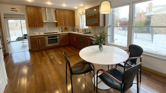 kitchen with dark wood-style floors, light countertops, wall chimney exhaust hood, and stainless steel oven