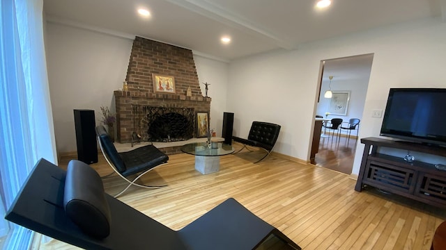 living room with a brick fireplace, baseboards, beam ceiling, recessed lighting, and hardwood / wood-style flooring