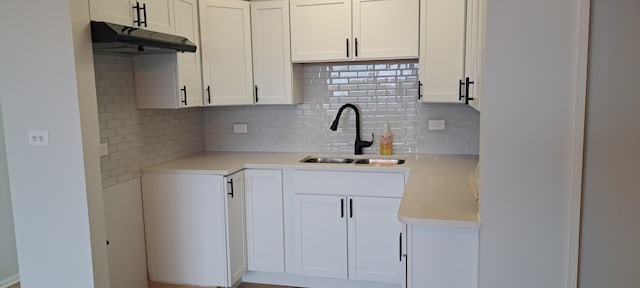 kitchen with backsplash, white cabinets, and sink