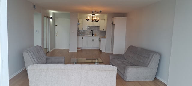 living room featuring light hardwood / wood-style flooring, a notable chandelier, and sink