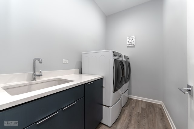 clothes washing area featuring cabinets, separate washer and dryer, hardwood / wood-style floors, and sink