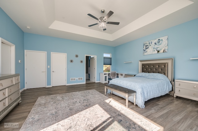 bedroom featuring a raised ceiling, ceiling fan, and dark hardwood / wood-style floors