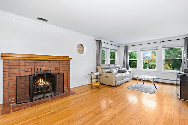 living room featuring crown molding, a fireplace, a baseboard heating unit, and light wood-type flooring