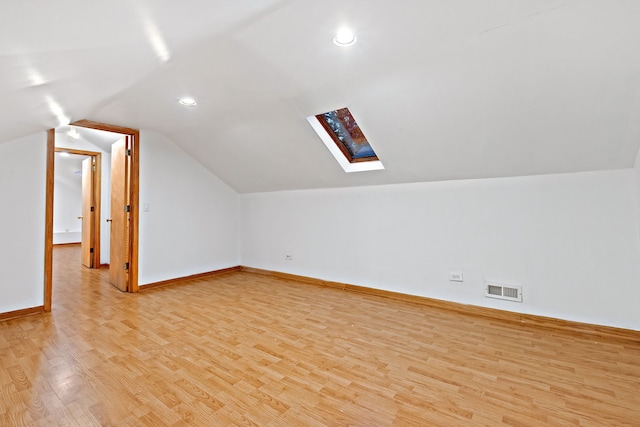 additional living space featuring light hardwood / wood-style flooring and lofted ceiling with skylight