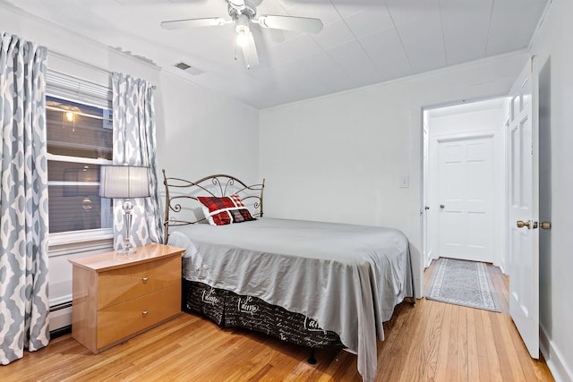 bedroom with a baseboard radiator, ceiling fan, and light hardwood / wood-style flooring