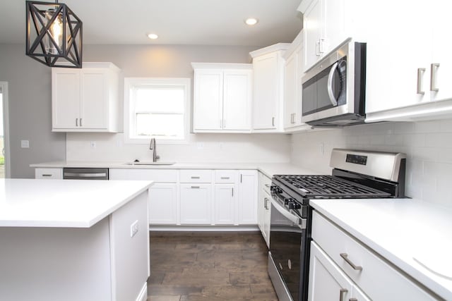 kitchen featuring backsplash, dark wood-type flooring, sink, decorative light fixtures, and stainless steel appliances