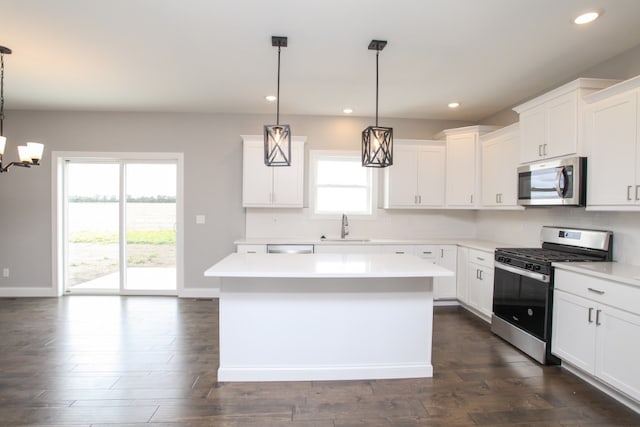 kitchen featuring sink, stainless steel appliances, white cabinetry, and hanging light fixtures